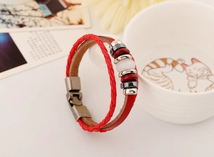 Dettaglio di un bracciale in pelle rossa intrecciata con perline di ceramica e fibbia bronzo
