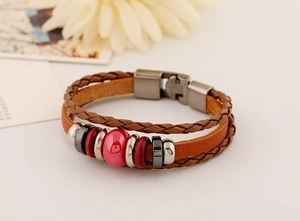 Detail of multi-layer braided leather bracelet with red ceramic beads and metal clasp