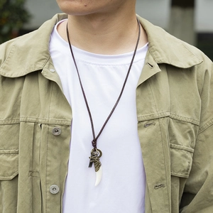 Détail du collier pour homme en cuir avec tête de loup en bronze et pendentif dent
