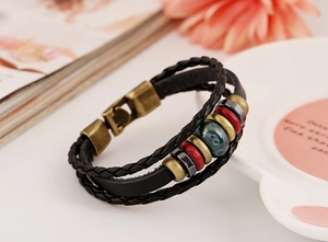 Detail of bohemian leather bracelet with bronze beads and a vintage green ceramic bead