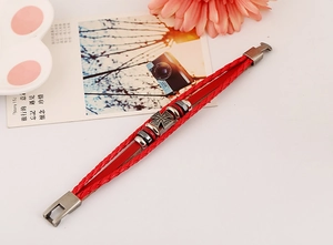 Macro detail of red multilayer leather punk bracelet with vintage metal cross charm