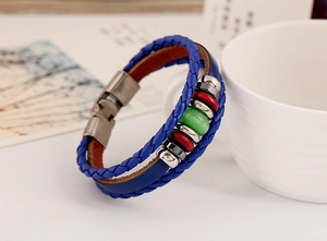 Detail of blue braided leather bracelet with multi-color beads next to a white cup
