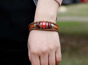 Detail of multi-layer brown leather bracelet with bold red beads and woven cords