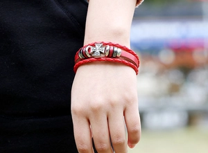 Detailed view of red braided leather punk bracelet with cross charm on a model wrist