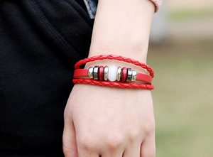 Dettaglio di bracciale in pelle rossa multistrato con pietra opale bianca e perline