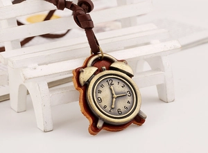 Macro shot of bronze clock pendant on leather backing with intricate dial details