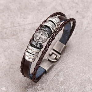 Close-up of vintage multi-layer leather bracelet with cross emblem and metallic beads
