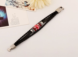 Detail of multilayer woven leather bracelet with red ceramic beads and metal clasp