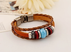 Detail of layered brown leather bracelet with blue ceramic bead and vintage metal clasp