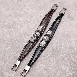 Retro beaded leather bracelets with vintage metal charms and cross patterns on stone background