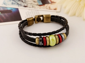 Gros plan d'un bracelet en cuir multicouche avec perles en céramique et fermoir bronze