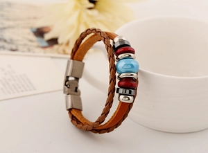 Detail of vintage braided leather bracelet with blue ceramic bead and wooden accents