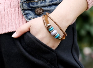 Gros plan d'un bracelet multicouche en cuir vintage avec perles turquoise au poignet