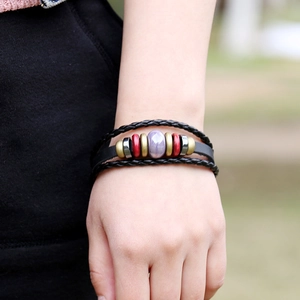 Multilayer braided leather bracelet featuring a central purple bead in a natural outdoor setting