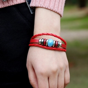 Multilayer red leather woven bracelet with blue ceramic bead on wrist in natural light