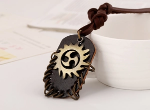 Detail of vintage rock leather necklace with bronze gear pendant and braided cord