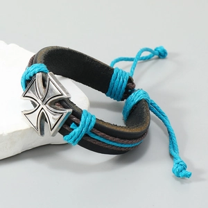 Macro detail of men's leather bracelet with blue woven cord and silver metal cross