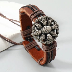Détail d'un bracelet vintage multicouche en cuir avec crânes en métal et corde tressée
