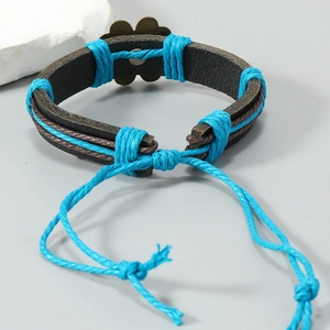 Détail d'un bracelet en cuir tressé à la main avec cordon bleu et breloque fleurie