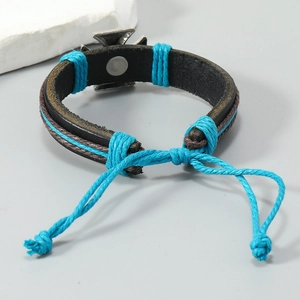Close-up of woven leather bracelet with cross charm and turquoise hemp rope detail