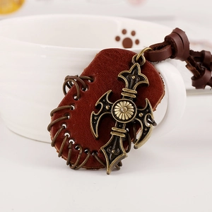 Retro punk leather necklace with a bronze gothic cross pendant on a white ceramic mug