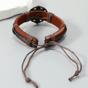 Détail d'un bracelet en cuir marron fait main avec breloque vintage en métal