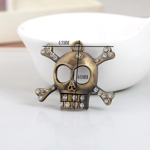 Detailed view of antique bronze skull pendant with rhinestones and measurement annotations