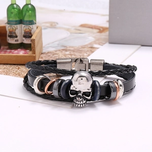 Close-up of multilayer leather bracelet with silver skull charm and metallic ring accents