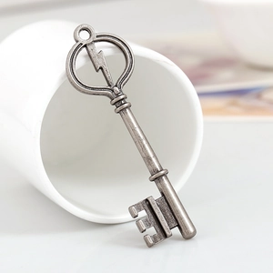 Vintage antique silver lightning key alloy pendant displayed on a white ceramic cup