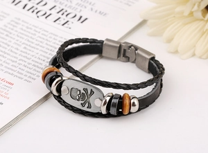 Detail of punk leather bracelet with skull metal plate and beaded layers on white desk