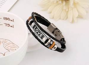 Detail of multi-layer braided leather bracelet with LOVE metal plate on ceramic cup