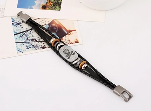 Close-up of punk leather bracelet featuring a metal skull charm and woven layers