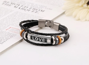 Detail view of multi-layer braided leather bracelet with LOVE silver plate and wooden beads