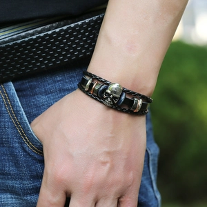 Close-up of punk style multi-layer leather bracelet with silver skull and blue beads