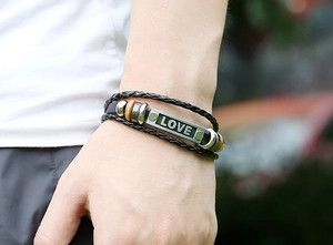 Close-up of a multi-layer woven leather bracelet featuring an engraved LOVE metal plate
