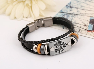 Detail of multilayer leather bracelet with wooden beads and engraved peace heart plate