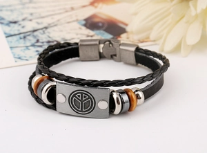 Macro detail of multi-layer leather bracelet with peace sign metal plate and clasp