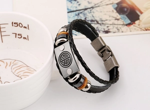 Detail of multi-layer braided leather bracelet featuring a vintage peace sign metal plate