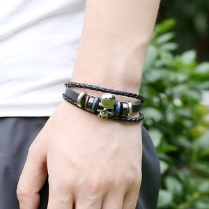 Punk style multi-layer braided leather bracelet with silver skull charm on male wrist