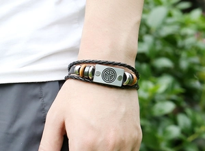 Detail of multi-layer leather bracelet with metal peace symbol and wooden beads in nature