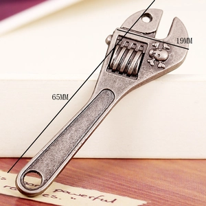 Detail view of antique silver wrench pendant with skull relief showing 65mm x 19mm size