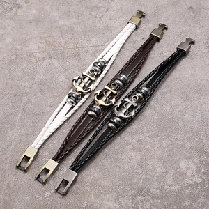 Detail of three-piece nautical leather braided bracelets with antique metal anchors