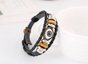 Macro shot of retro braided leather bracelet with blue evil eye pendant and metal beads