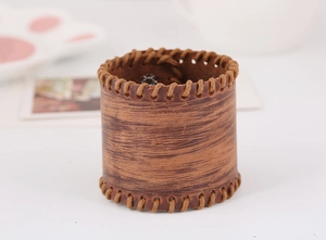 Detailed close-up of wide vintage brown leather bracelet with stitched edges and texture