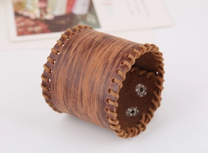 Detail of vintage brown wide leather wristband with braided edges and silver metal snaps