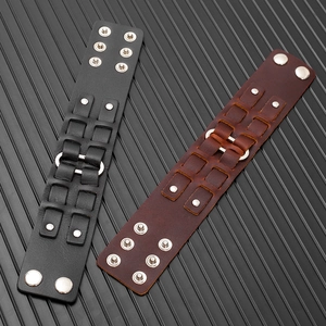 Dettaglio dei bracciali regolabili in pelle con borchie metalliche e anelli