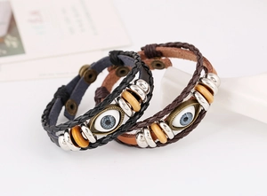 Close-up of woven leather bracelets with evil eye charm and natural wooden beads