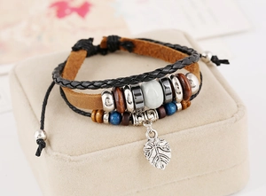 Détail d'un bracelet en cuir multicouche avec perles en bois et breloque feuille argentée