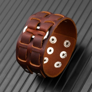 Dettaglio del bracciale punk largo in pelle intrecciata con anelli e bottoni automatici