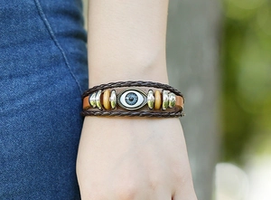 Close-up of vintage multi-layer leather bracelet with evil eye bead and wooden accents